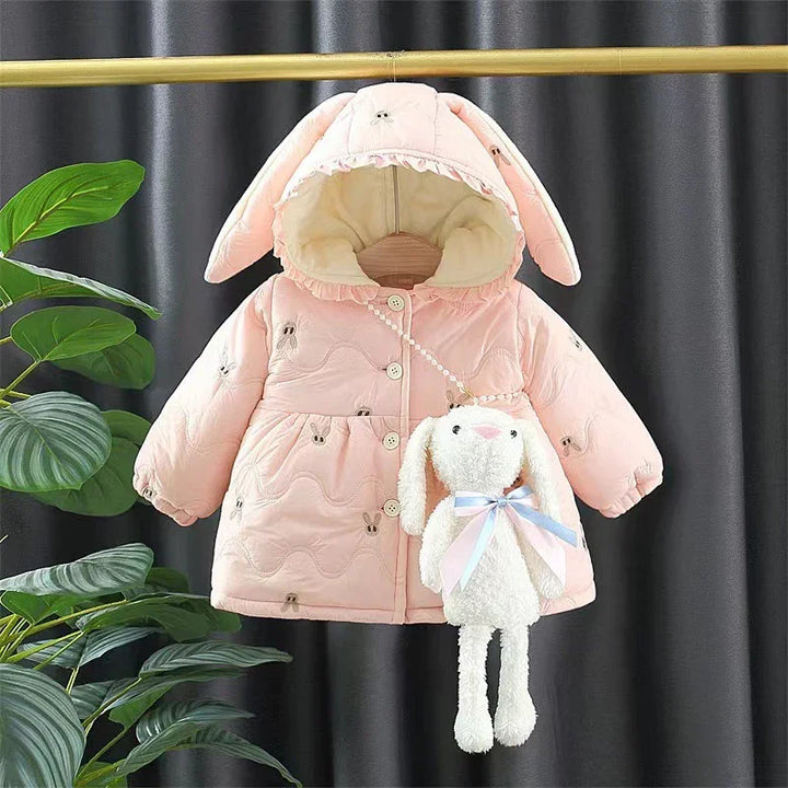 Pink baby jacket with bunny ear hood and matching plush bunny bag hanging on a golden rack