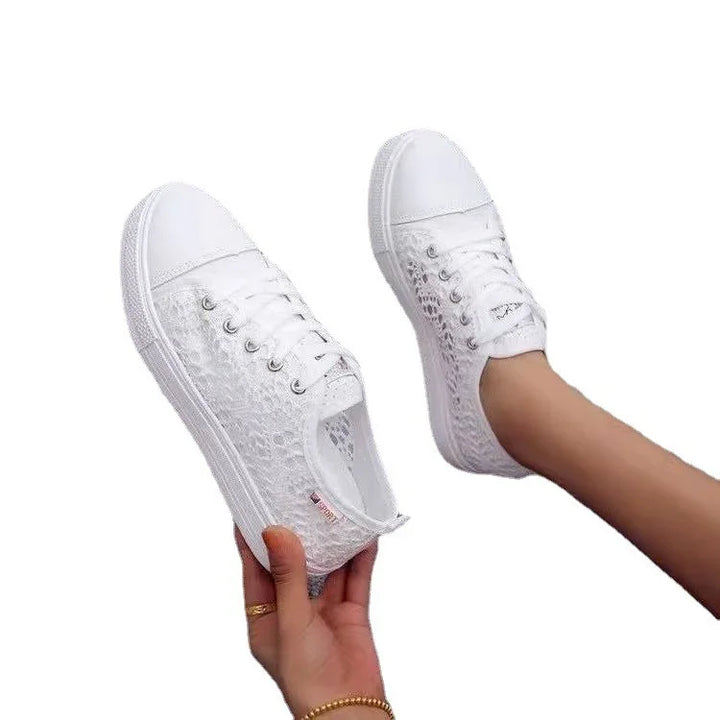 White lace casual sneakers with rubber soles, worn on feet and held by hand, on white background