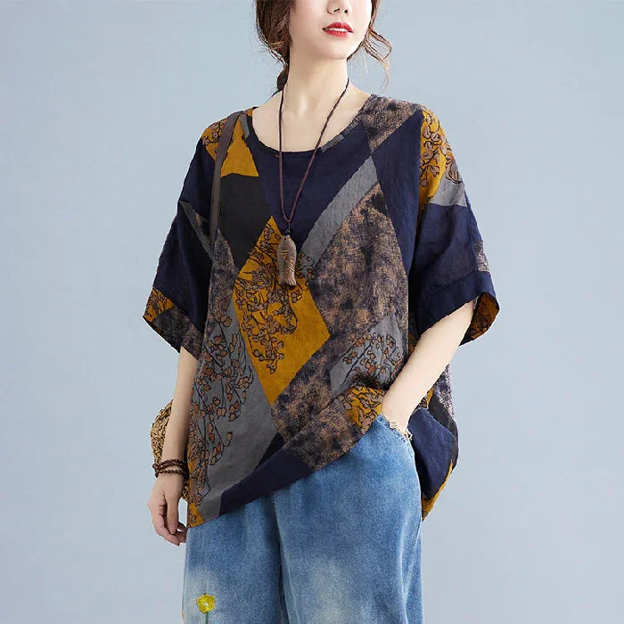 Woman wearing loose navy, mustard, and gray geometric patterned casual top with short sleeves and relaxed fit