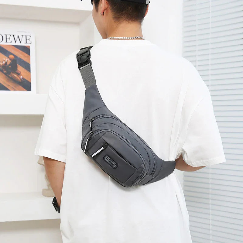 Man wearing black crossbody sling bag with multiple zippered compartments and adjustable strap