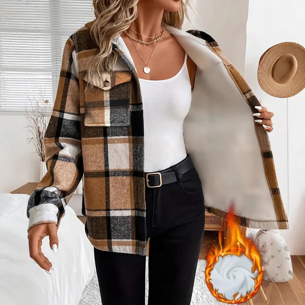 Woman wearing brown plaid fleece jacket over white tank top and black pants in cozy modern room