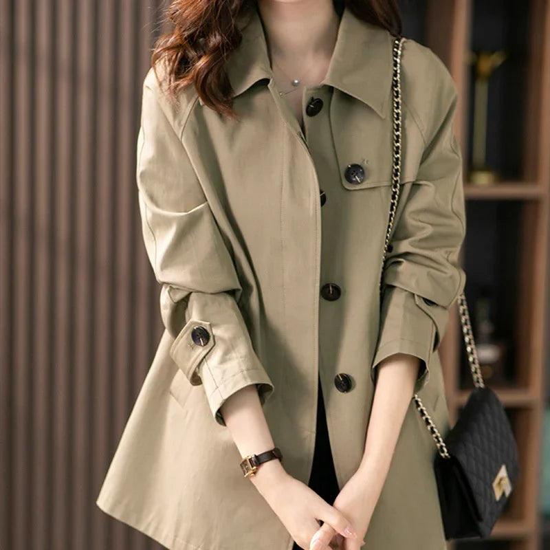 Woman wearing beige trench coat with black buttons and carrying black quilted chain bag