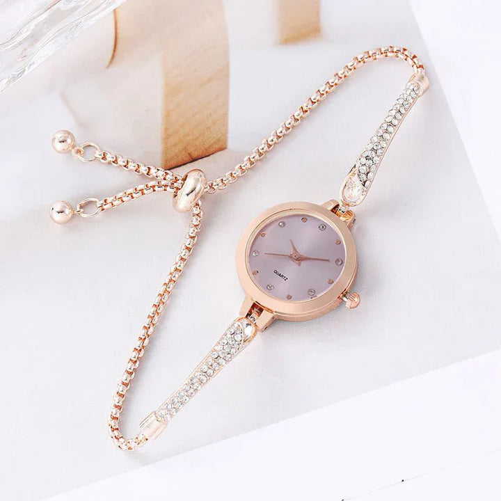 Elegant rose gold quartz women's bracelet watch with crystal-studded chain links on white surface