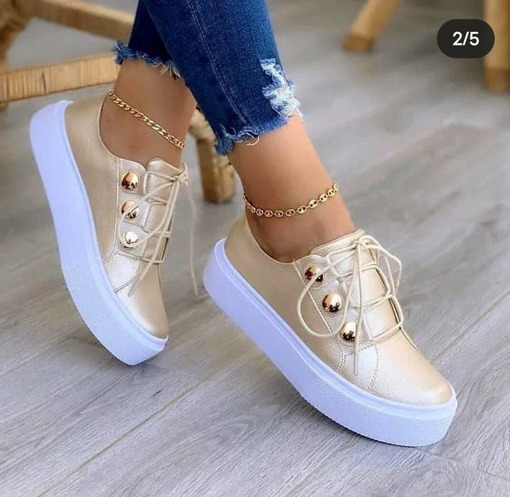 Gold metallic platform sneakers with white soles worn with ripped blue jeans and gold anklets