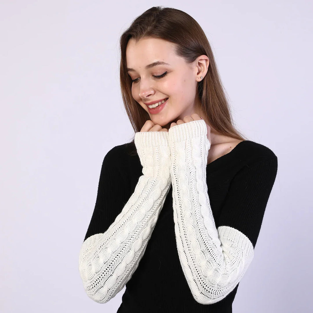 Woman wearing black sweater with long white knit fingerless gloves against plain background