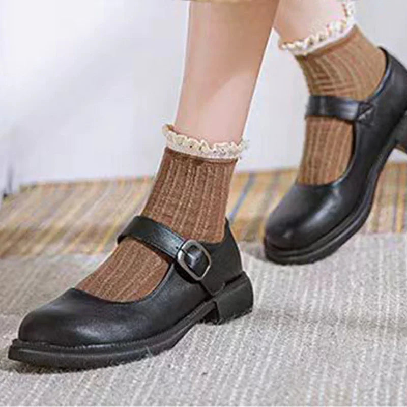 black Mary Jane shoes with buckle worn with brown frilled ankle socks on carpet