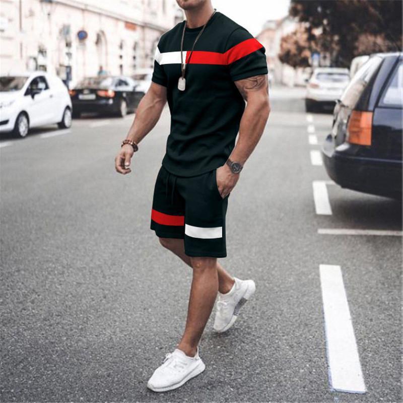 Man walking on city street wearing black athletic set with red and white stripes and white sneakers