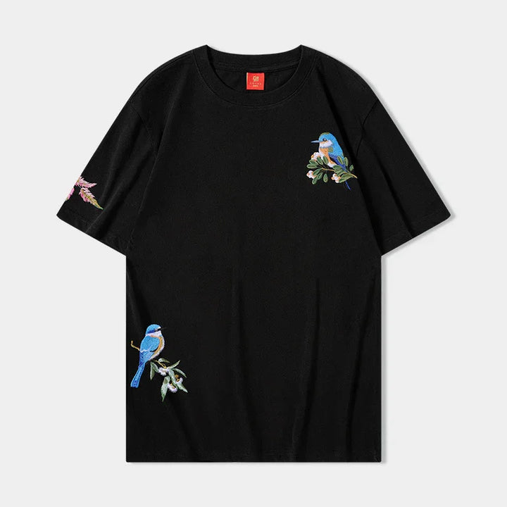 Black short-sleeve t-shirt with embroidered blue birds and floral designs on chest, sleeve, and hem