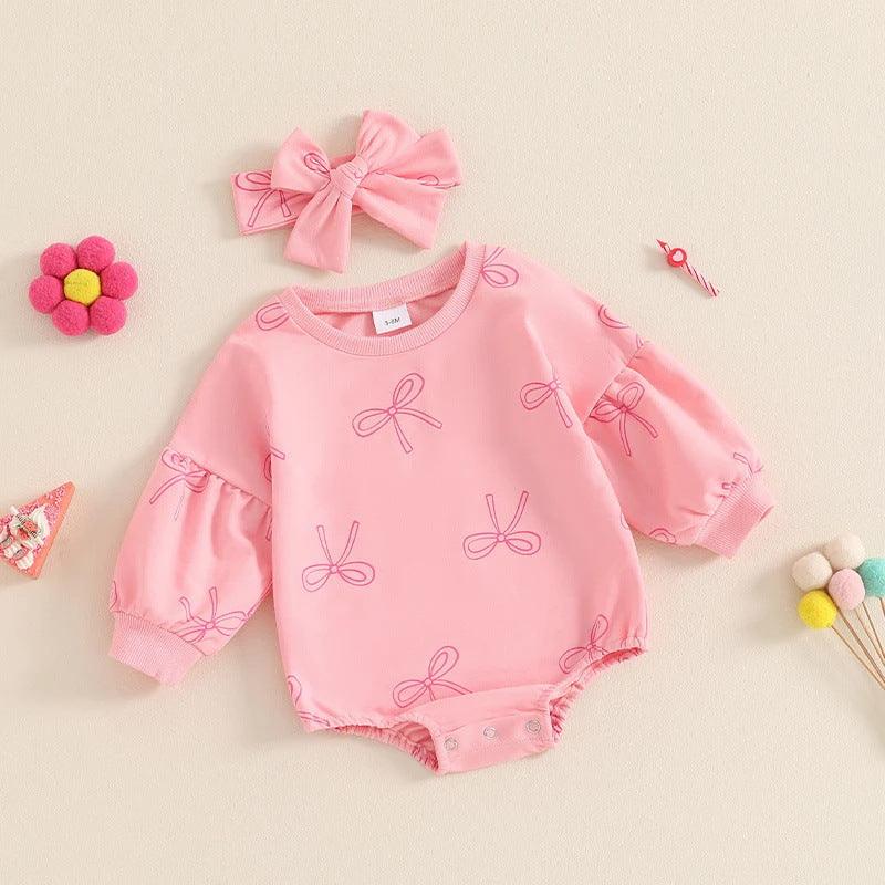 Pink baby romper with bow prints and matching headband, surrounded by colorful felt toys