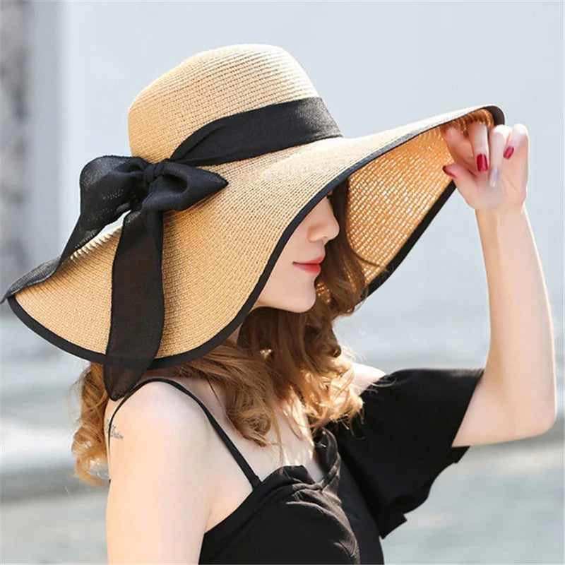 Woman wearing a wide-brimmed straw sun hat with black ribbon bow and black dress outdoors