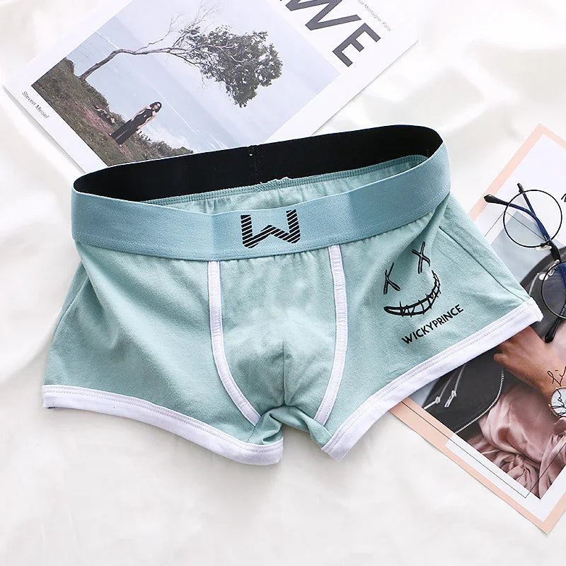 Light blue men's boxer briefs with black waistband and white trim, featuring a smiling face design and 'WICKYPRINCE' text