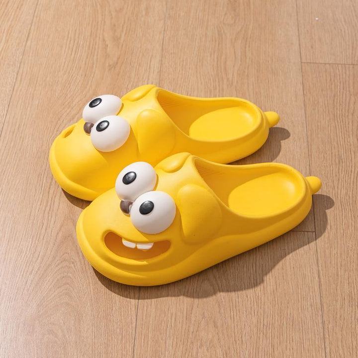 Yellow cartoon character slippers with bulging eyes on wooden floor