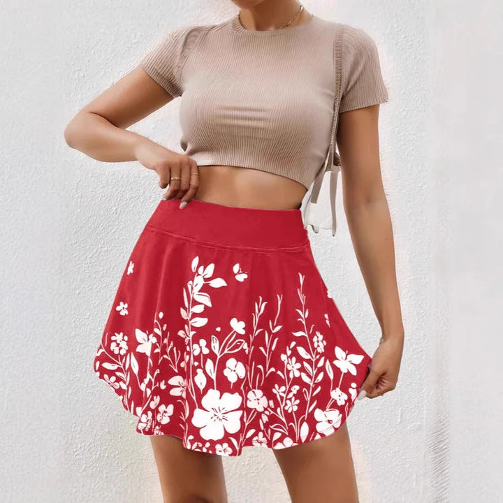 Woman wearing red floral print skirt and beige cropped ribbed top against white wall