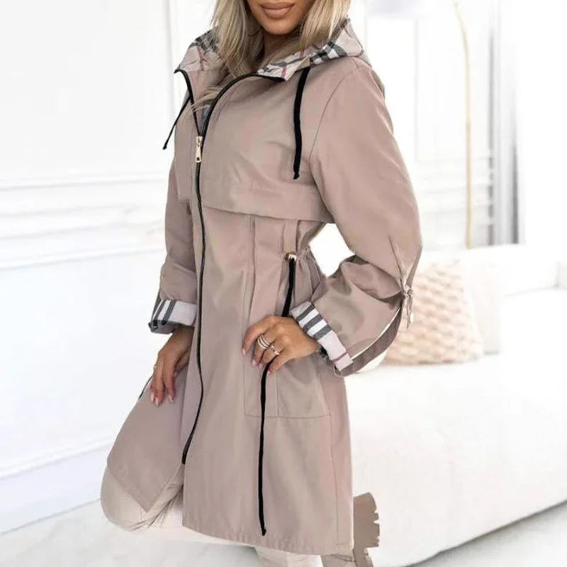 Woman wearing stylish beige trench coat with striped cuffs and black drawstring zipper
