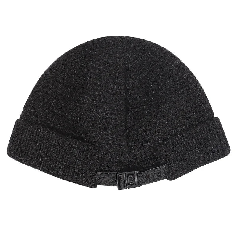 Black knit beanie hat with folded brim and adjustable strap buckle on white background