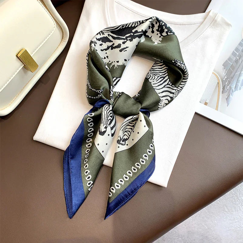 Silk scarf with zebra print and blue border styled on white shirt with cream handbag on brown surface