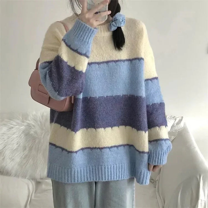 Person wearing cozy oversized striped sweater in blue, purple, and cream with soft texture indoors