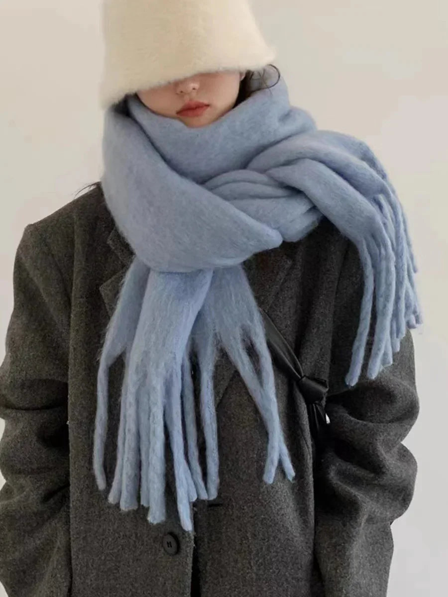 Person wearing oversized light blue wool scarf, dark gray coat, and fuzzy white bucket hat