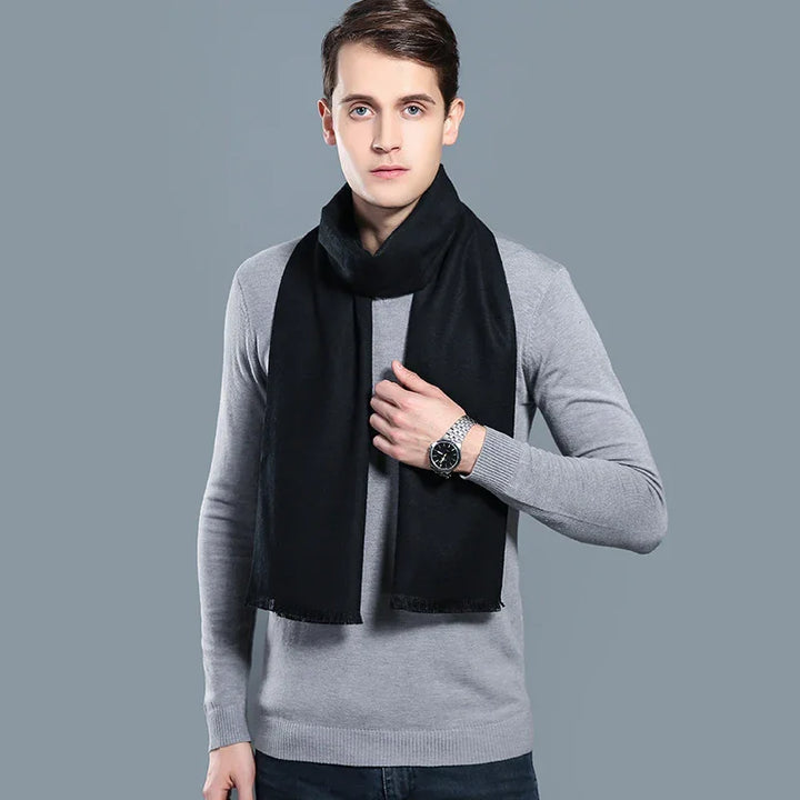 Young man wearing black scarf and gray sweater against plain gray background