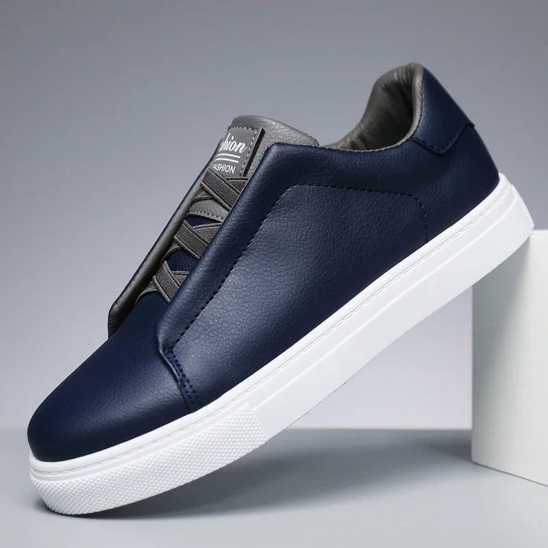 Navy blue leather casual sneaker with white rubber sole and black padded tongue on gray background