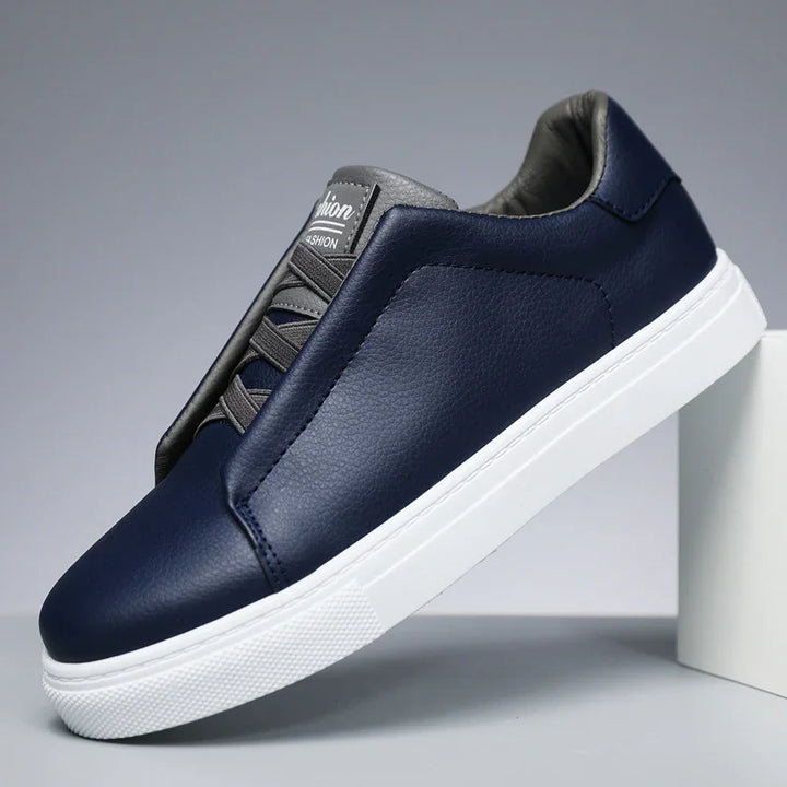 Navy blue leather casual sneaker with white rubber sole and black padded tongue on gray background