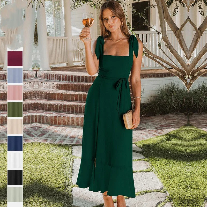 Woman in green sleeveless dress holding wine glass in sunny garden with brick steps