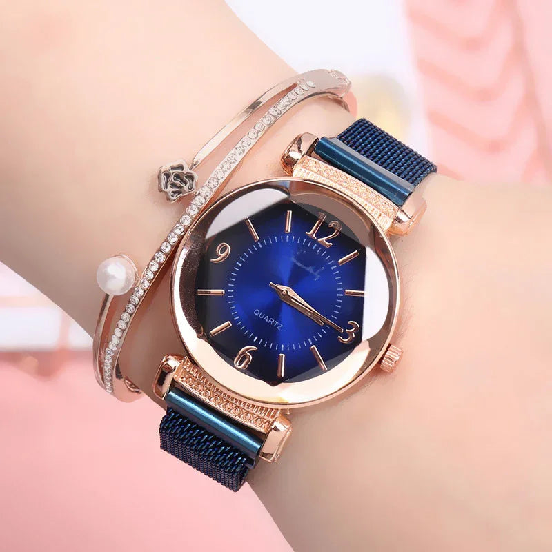 Elegant rose gold wristwatch with blue dial and mesh strap, paired with rhinestone and pearl bracelets