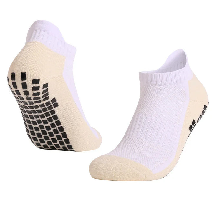 White low-cut athletic socks with beige soles and black non-slip grips on heels against white background