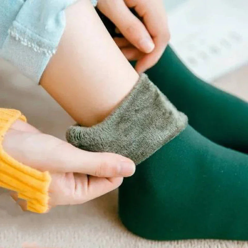 Hands adjusting warm green fleece-lined thermal socks on person's ankle