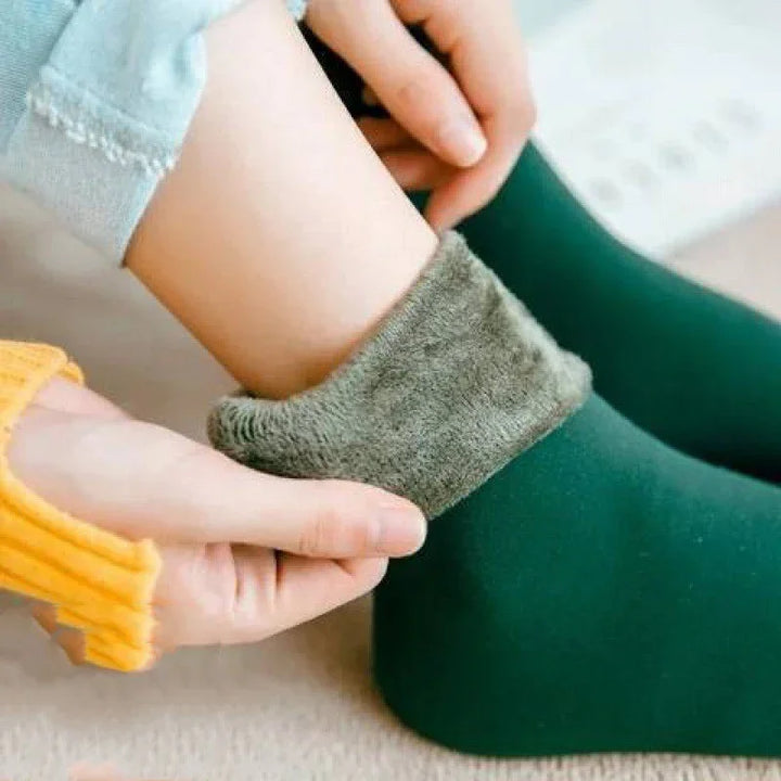 Hands adjusting warm green fleece-lined thermal socks on person's ankle