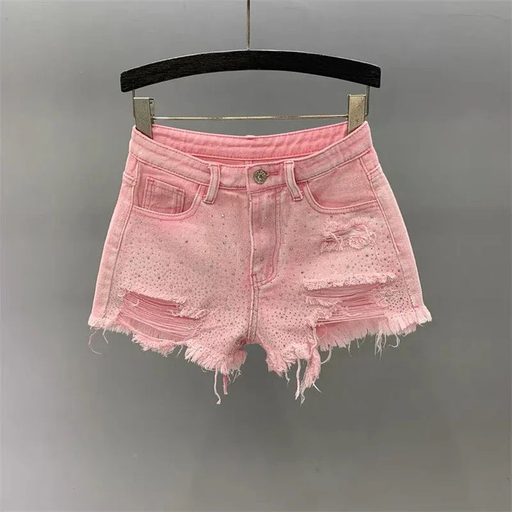 Pink distressed denim shorts with frayed hem and small rhinestones hanging on black hanger