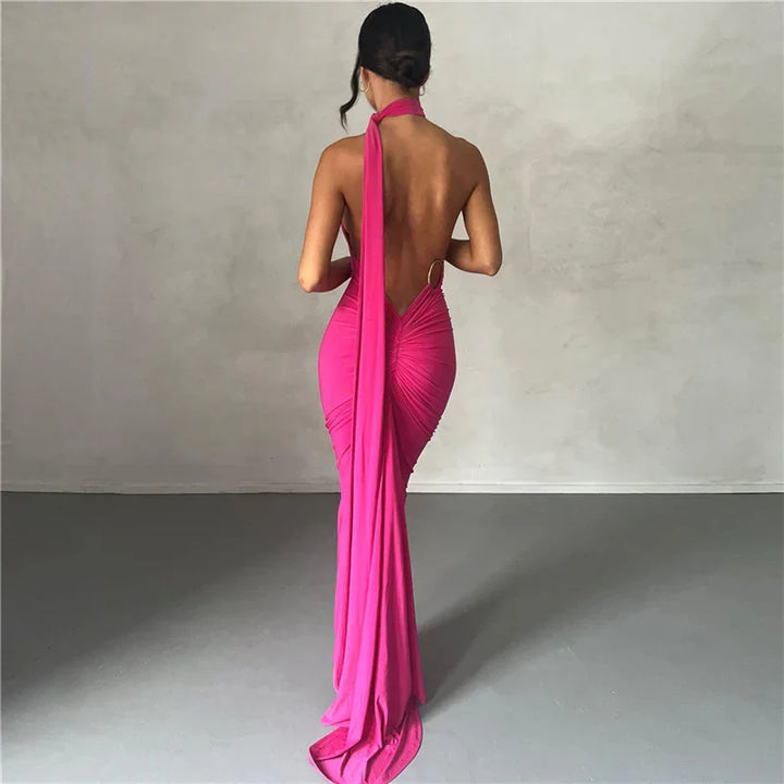 Woman wearing a backless fuchsia evening gown with floor-length drape in a minimalist studio