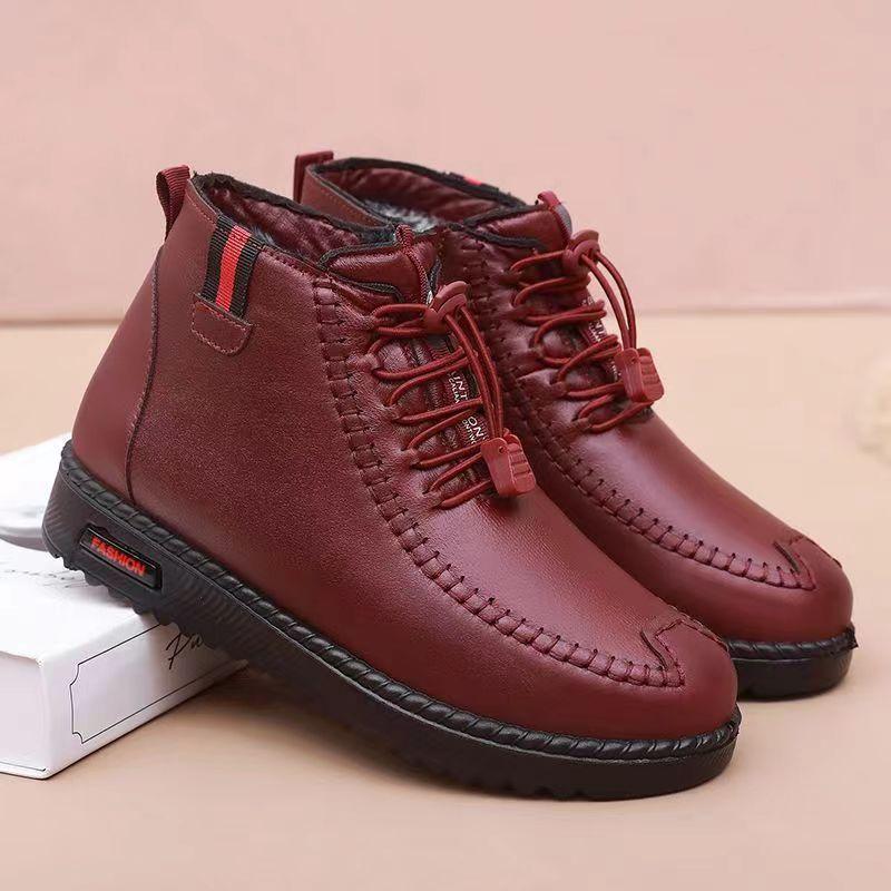 Red leather casual ankle boots with black sole and lace-up closure on beige background