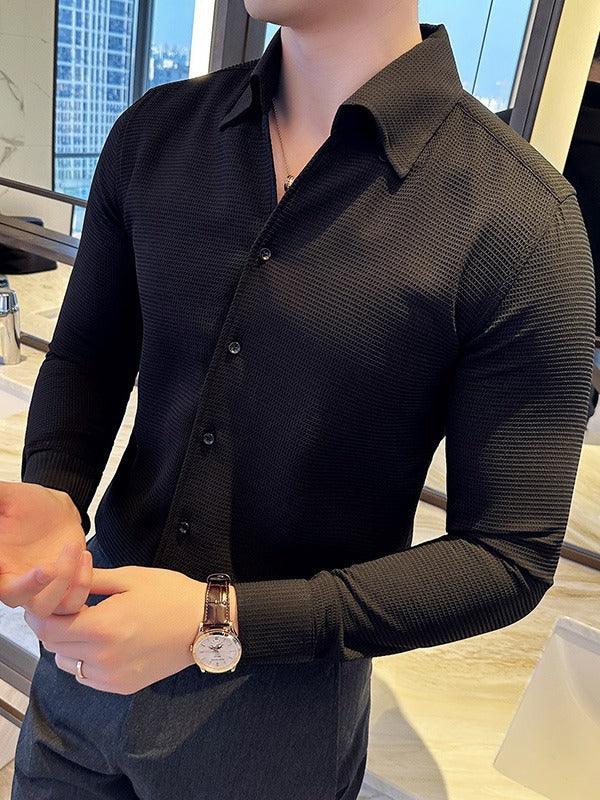 Man wearing black textured button-up shirt and wristwatch indoors with city view background