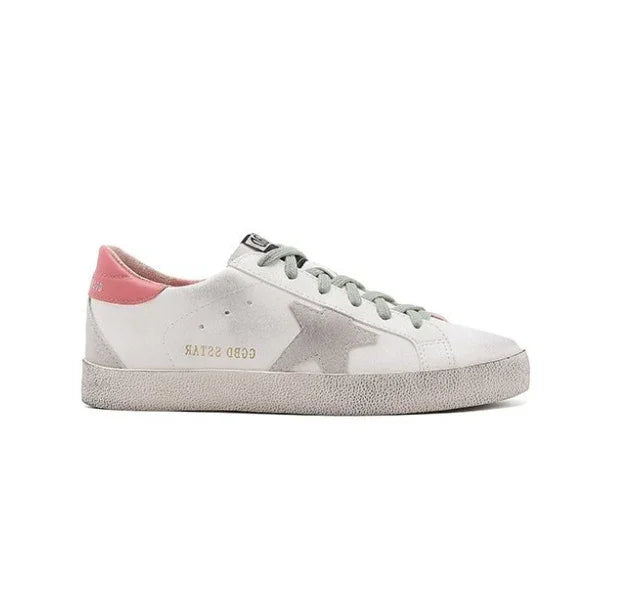 White low-top sneaker with gray star design, pink heel tab, and gray laces on white background