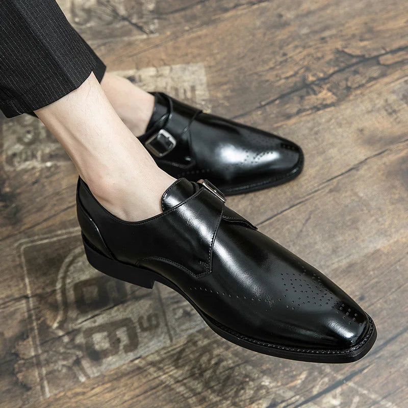 Polished black leather monk strap dress shoes on wooden floor with formal trousers