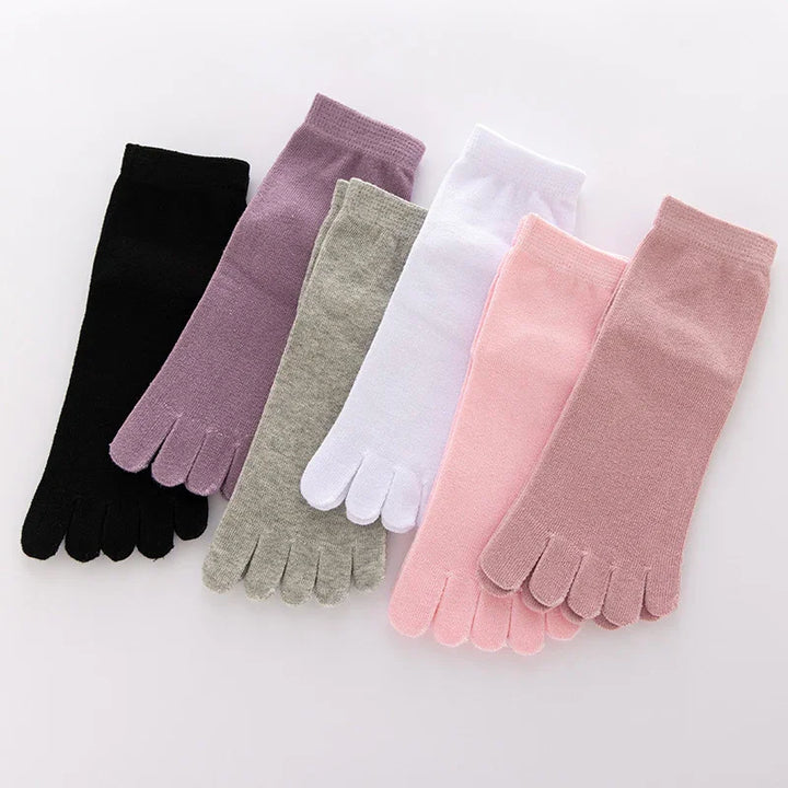 Set of six pairs of toe socks in black, purple, gray, white, light pink, and rose pink on white background