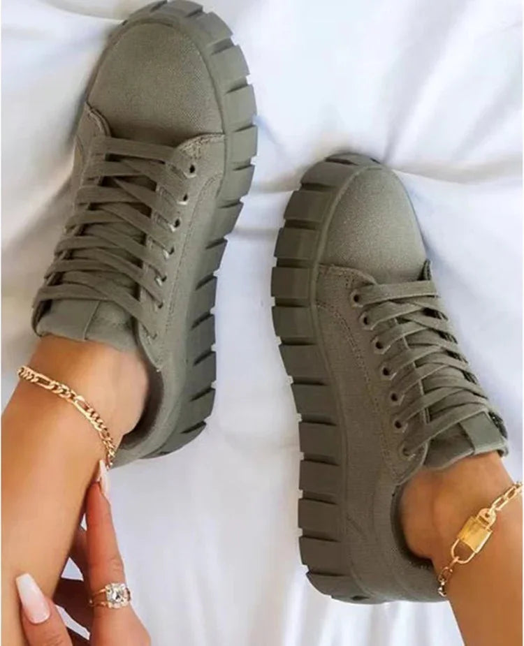 Close-up of feet wearing chunky olive green platform sneakers with thick soles on white background