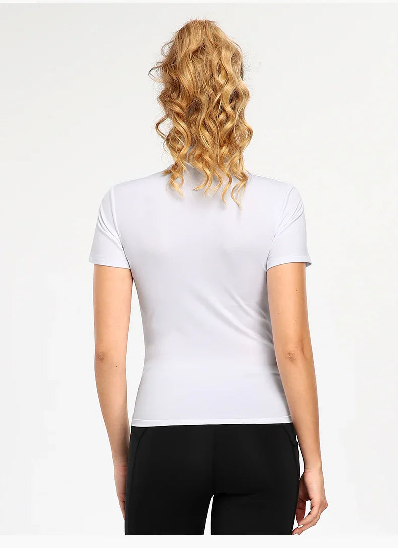 Back view of woman wearing a fitted white short-sleeve t-shirt and black pants with curly blonde hair