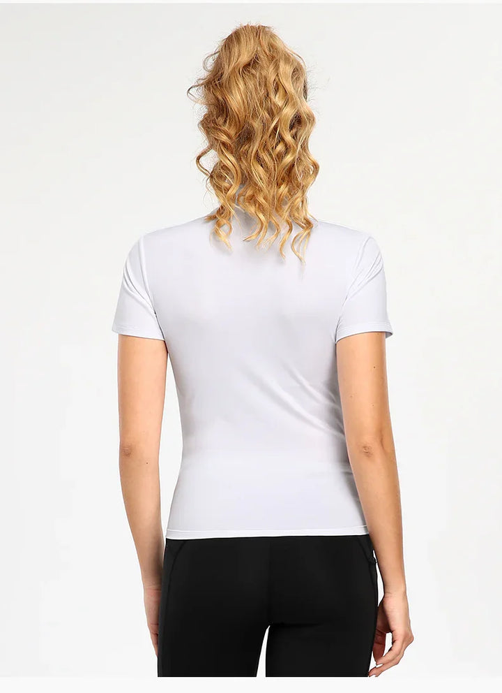 Back view of woman wearing a fitted white short-sleeve t-shirt and black pants with curly blonde hair