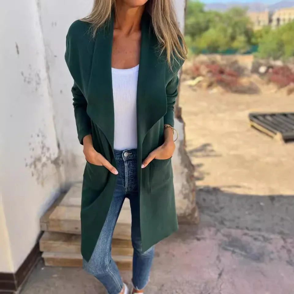 Woman wearing dark green open-front cardigan, white top, and blue jeans outdoors