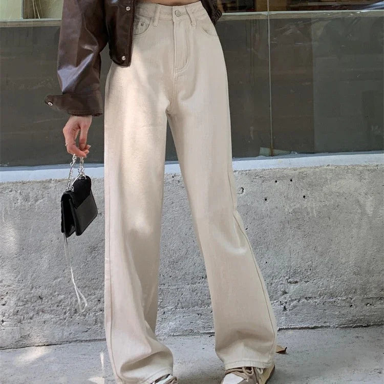 Person wearing beige wide-leg pants, brown leather jacket, holding black handbag with chain strap