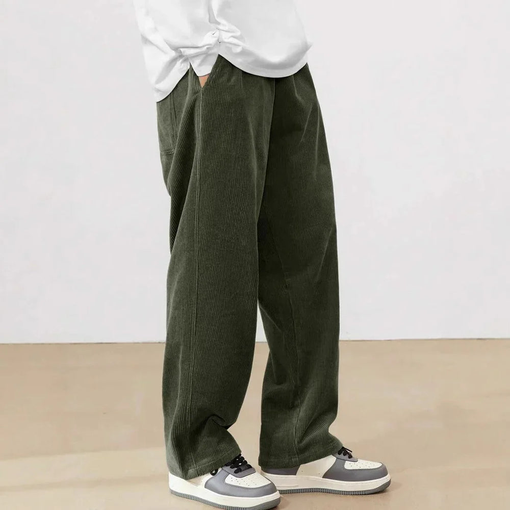 Person wearing dark green wide-leg corduroy pants paired with white and gray sneakers