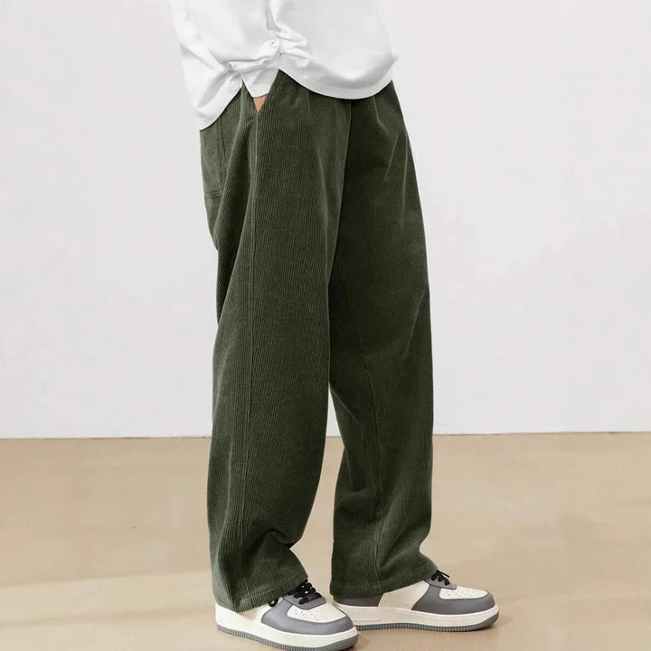 Person wearing dark green wide-leg corduroy pants paired with white and gray sneakers