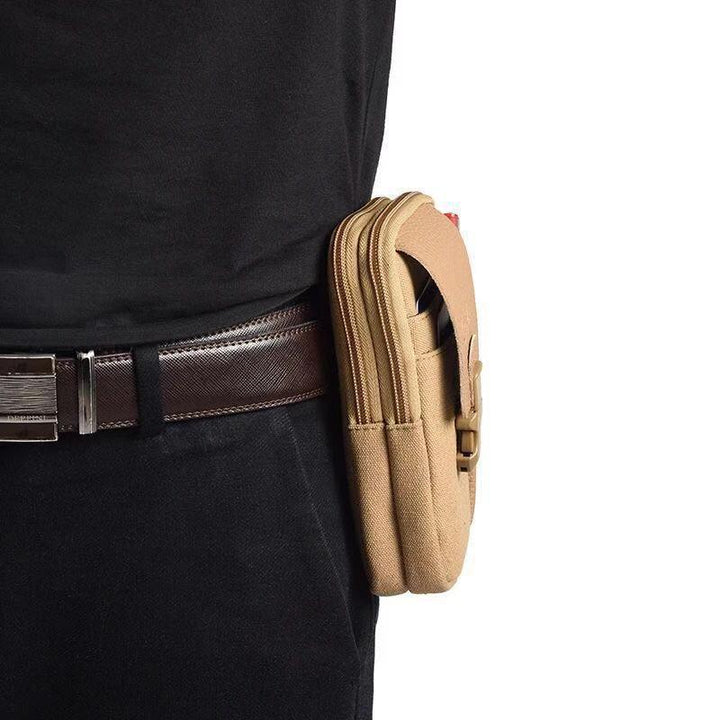 Tan canvas waist bag with two zippered compartments worn on a brown leather belt with black pants and black shirt