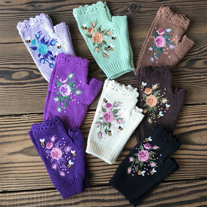 Set of colorful knitted fingerless gloves with floral embroidery and bee designs on wooden surface