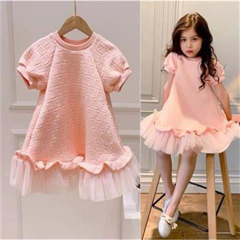 Pink textured short-sleeve girls dress with tulle hem, worn by a young girl sitting on stool