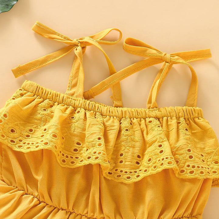 Close-up of yellow toddler dress with embroidered lace ruffle and tied shoulder straps