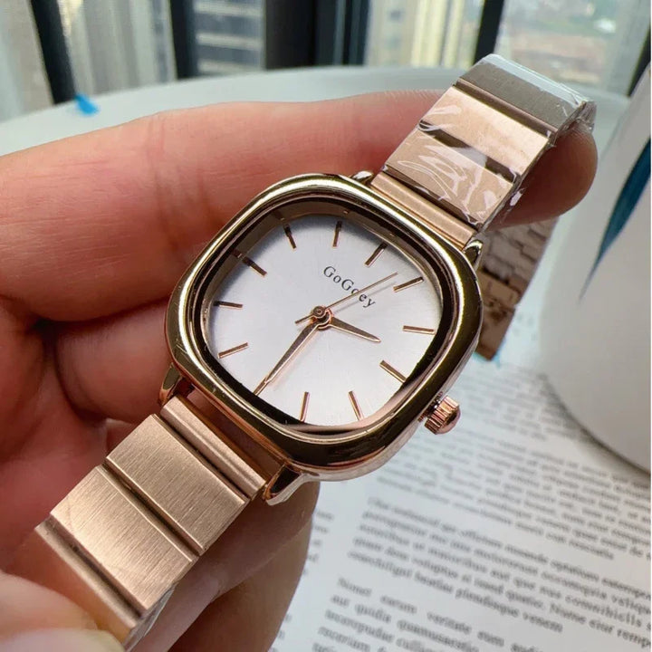 Hand holding rose gold GoGoeY wristwatch with square white dial and metal band