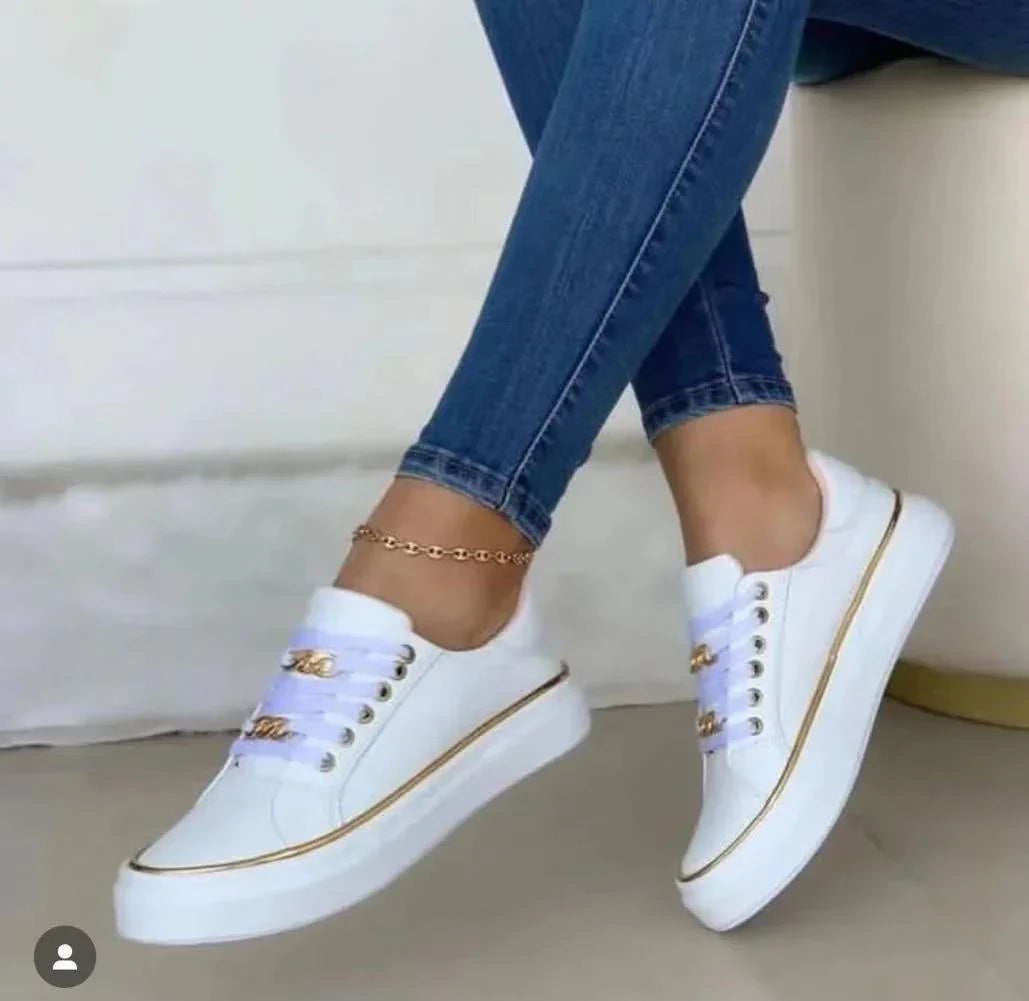 White platform sneakers with gold accents worn with blue skinny jeans and a gold anklet